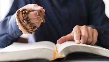 person-holding-rosary-with-cross-and-praying